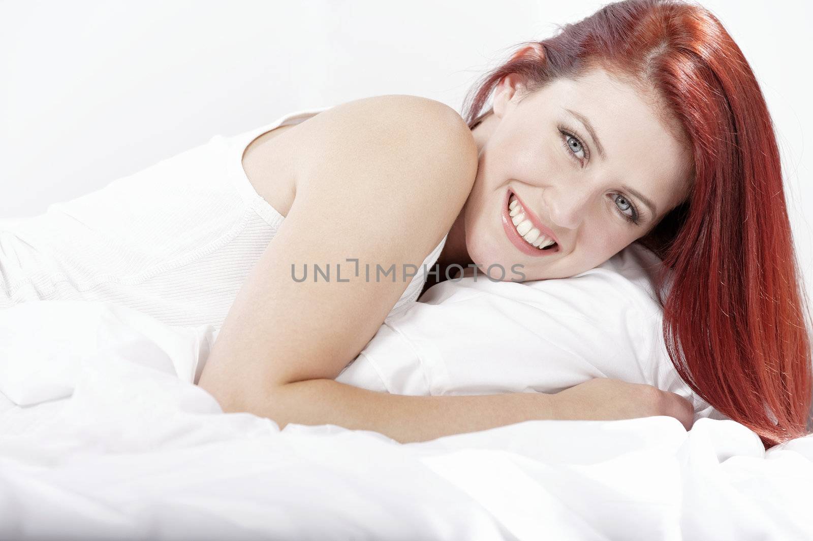 Young woman lying on her white bed at home relaxing