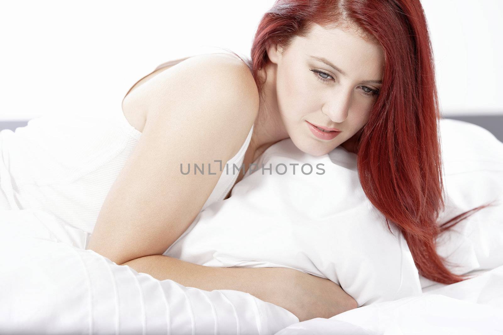 Young woman lying on her white bed at home relaxing