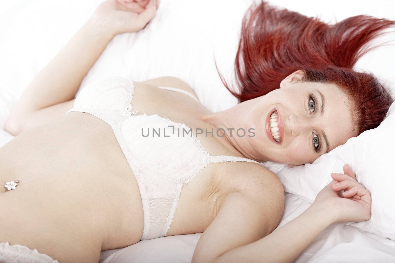 Attractive young woman lying on her bed in her underwear at home