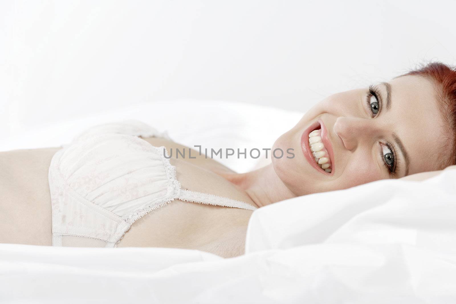 Attractive young woman lying on her bed in her underwear at home