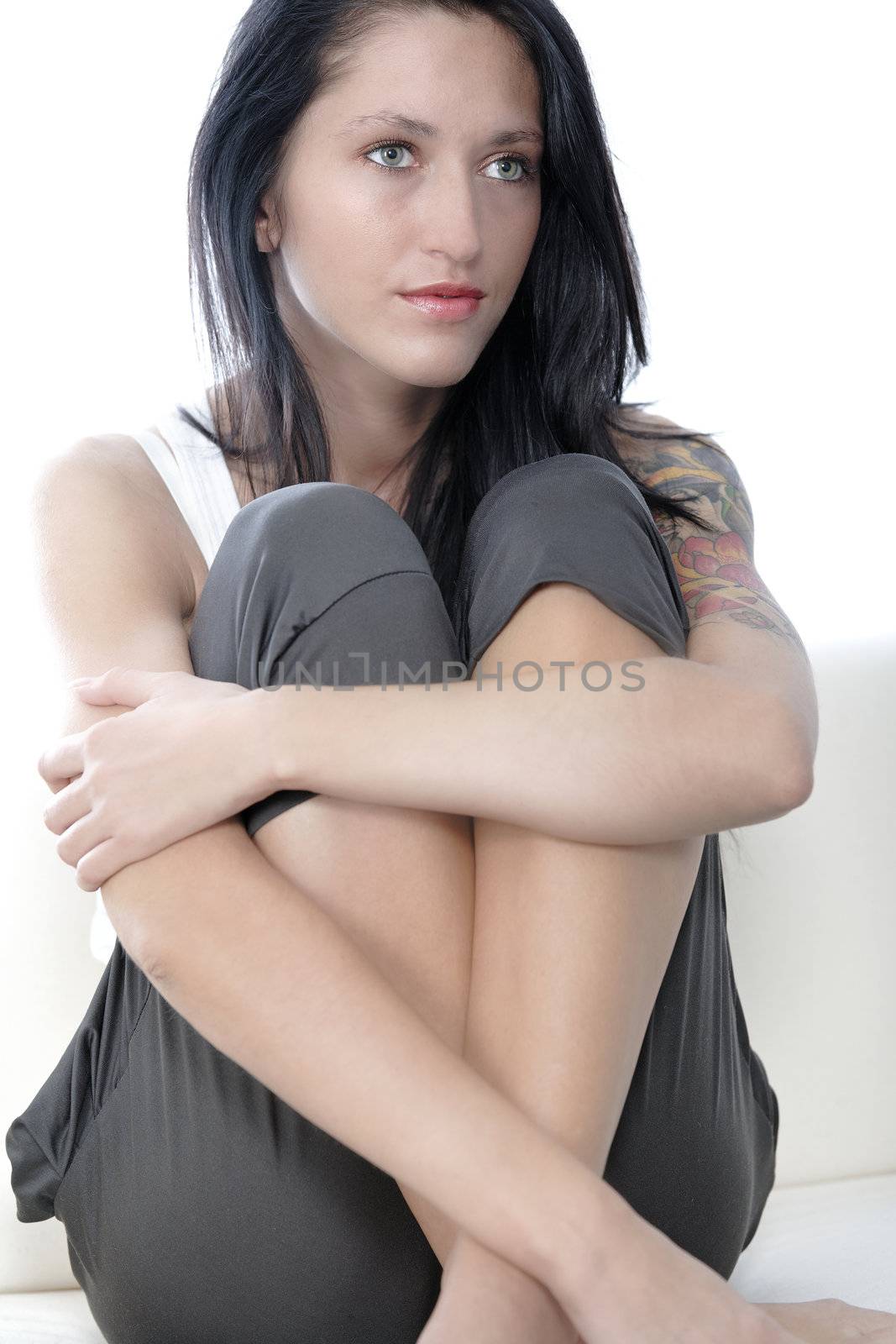 Beautiful young woman sat on a white sofa relaxing.