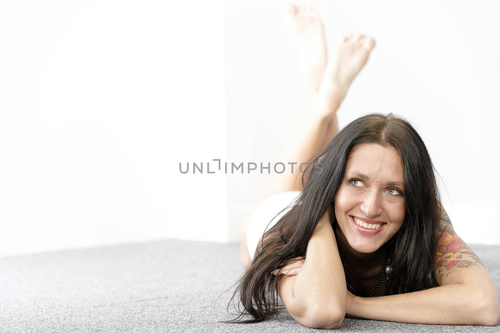 Beautiful young woman lying on her front on the floor smiling