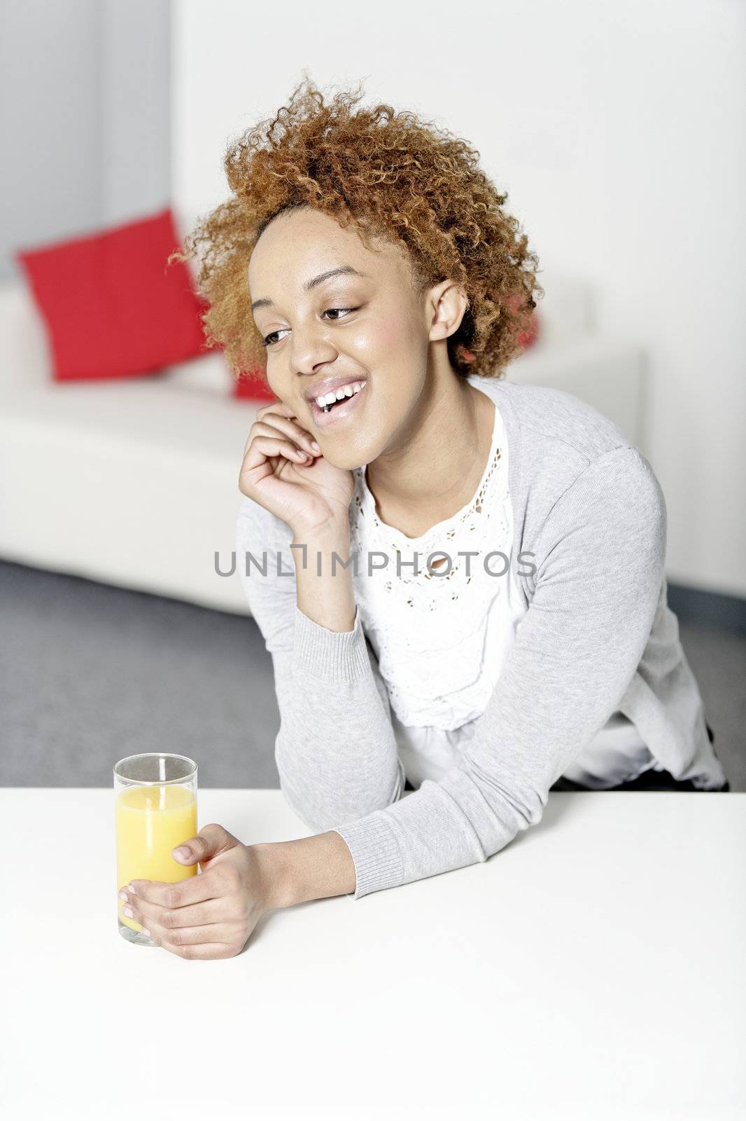 Attractive black woman  relaxing in living room with a glass of juice