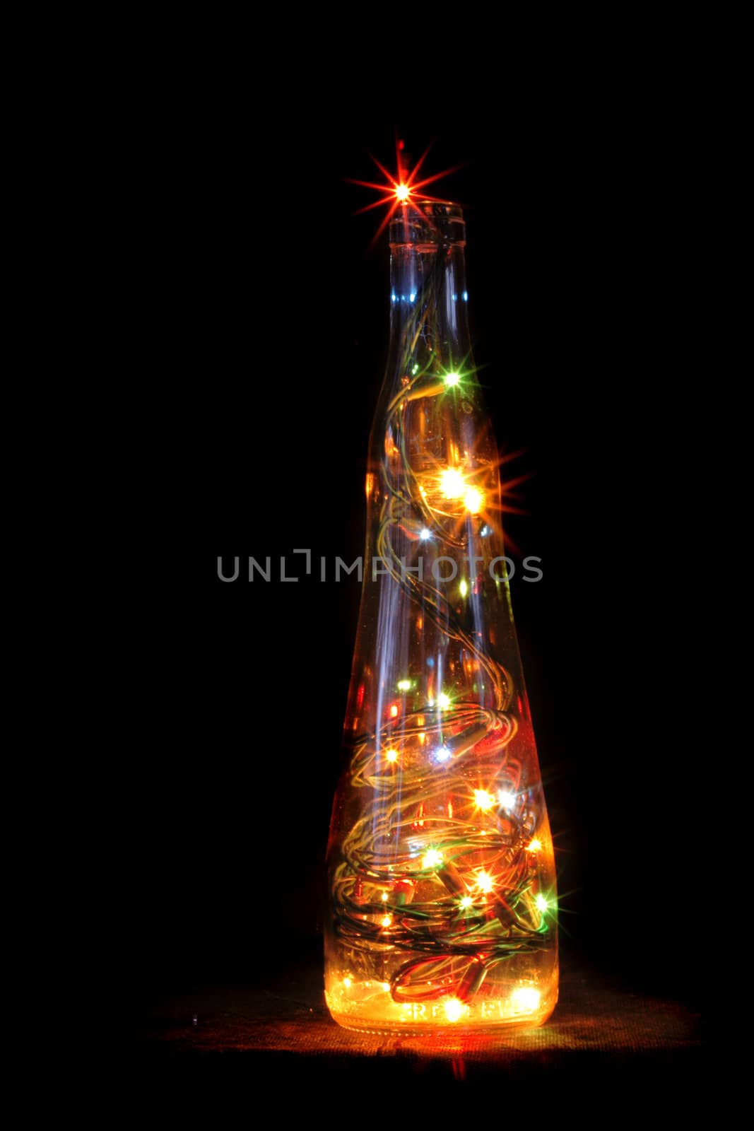 christmas alcohol bottle with color lights on red background