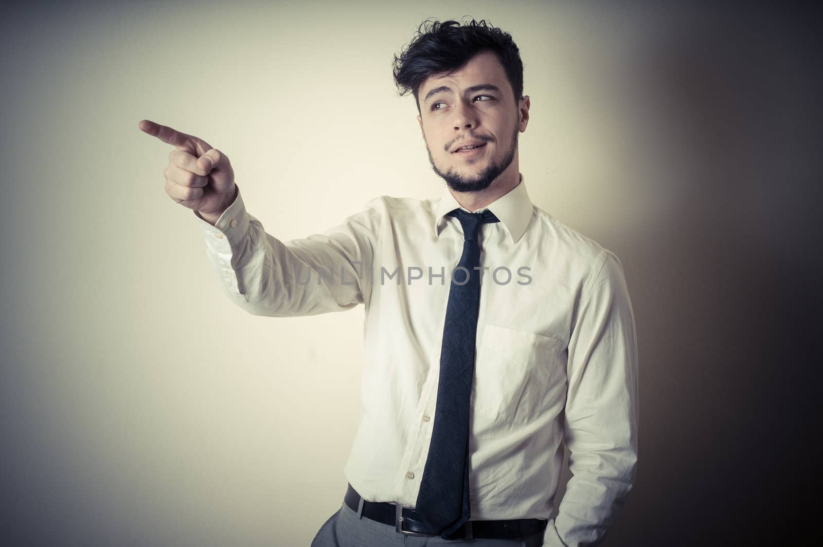 stylish modern guy with white shirt pointing on gray background