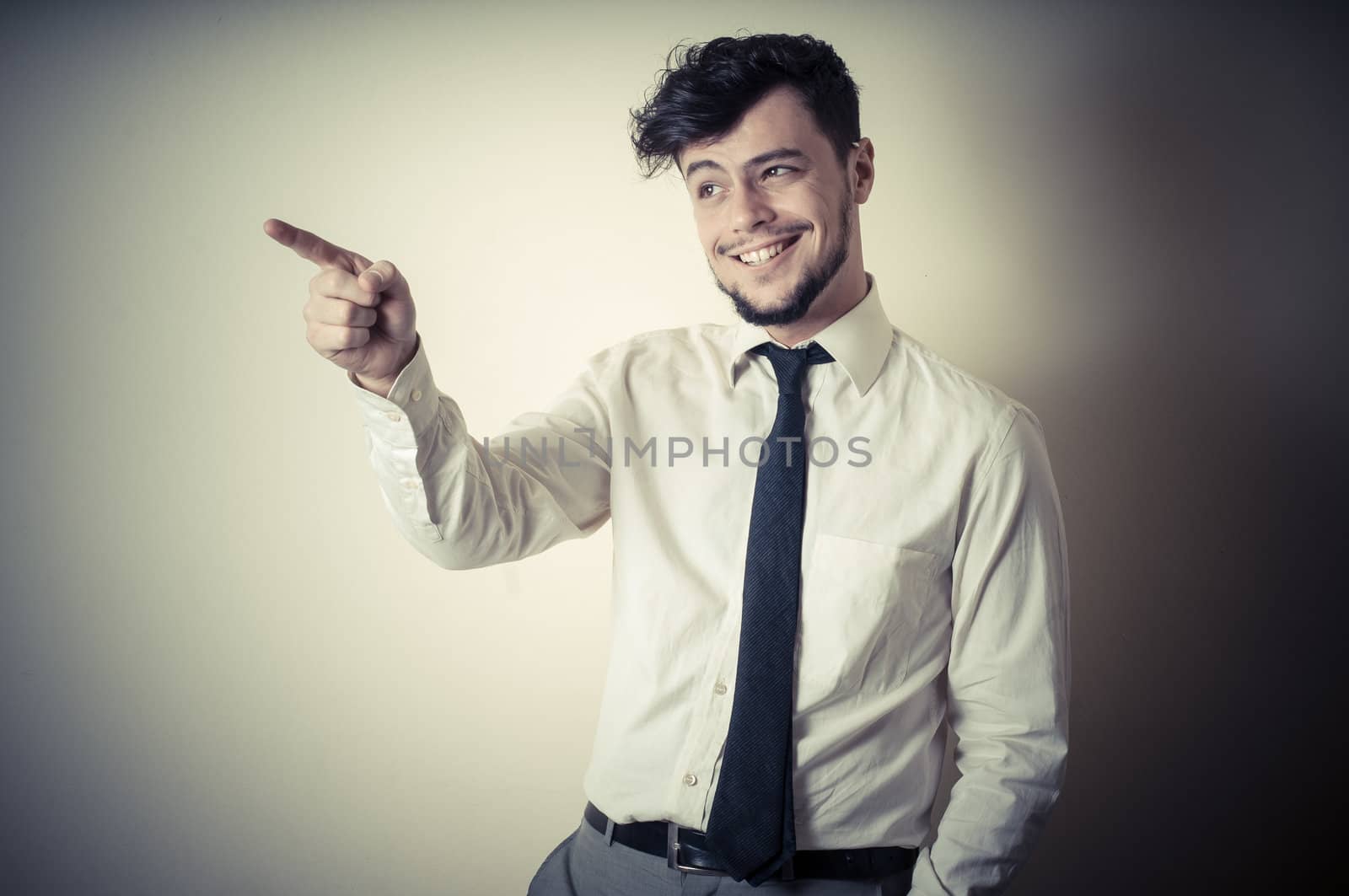 stylish modern guy with white shirt pointing on gray background