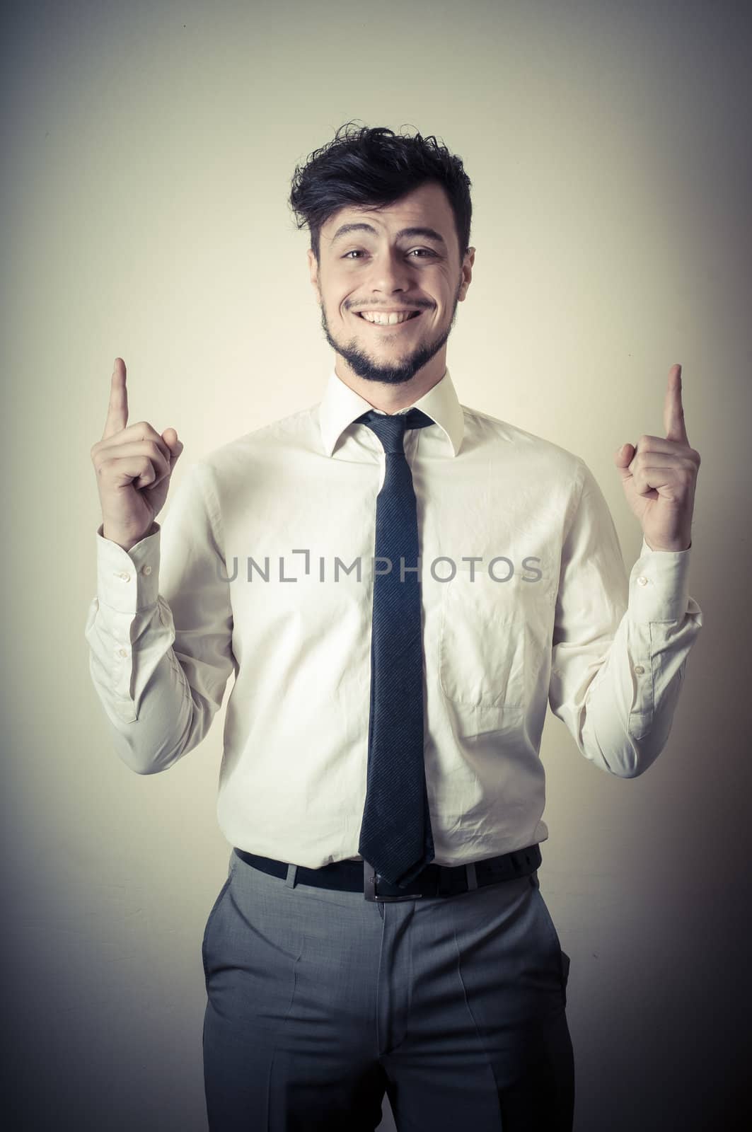 stylish modern guy with white shirt pointing on gray background