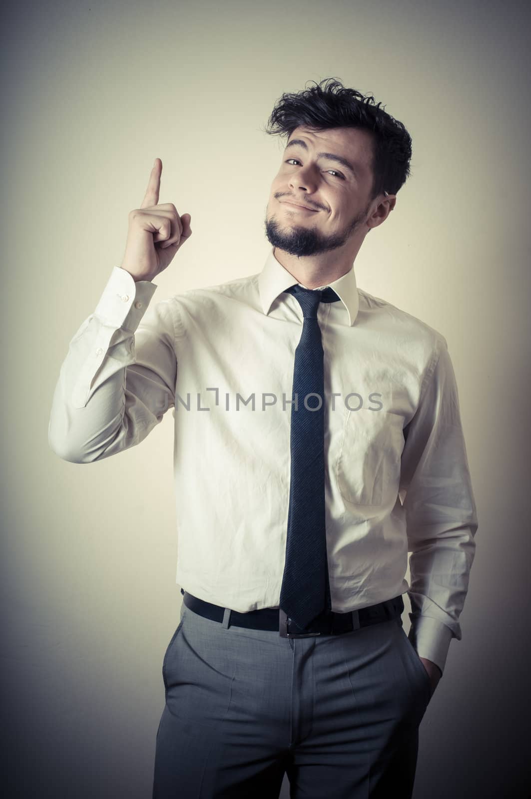 stylish modern guy with white shirt pointing on gray background