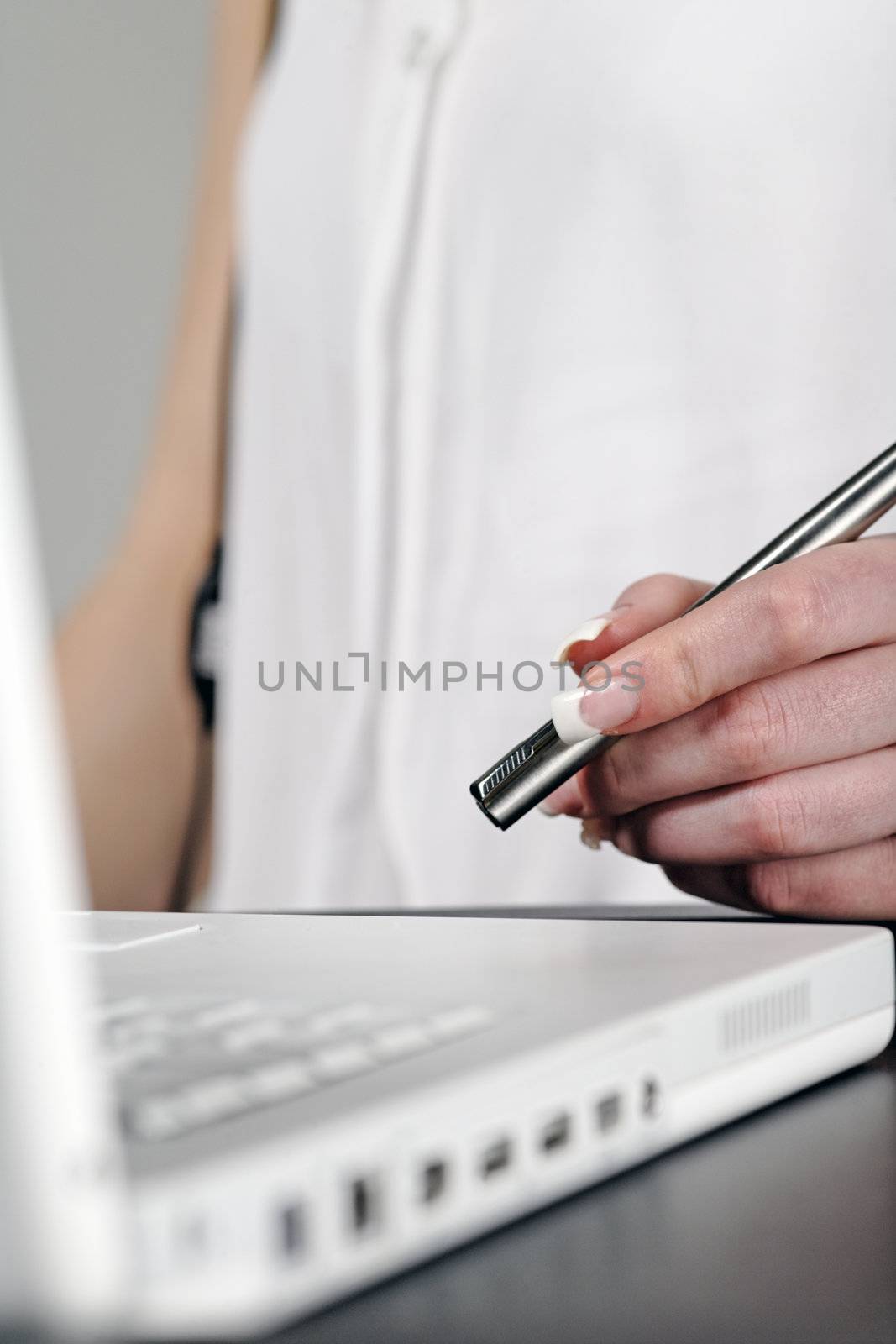 Woman using laptop while holding  pen at work