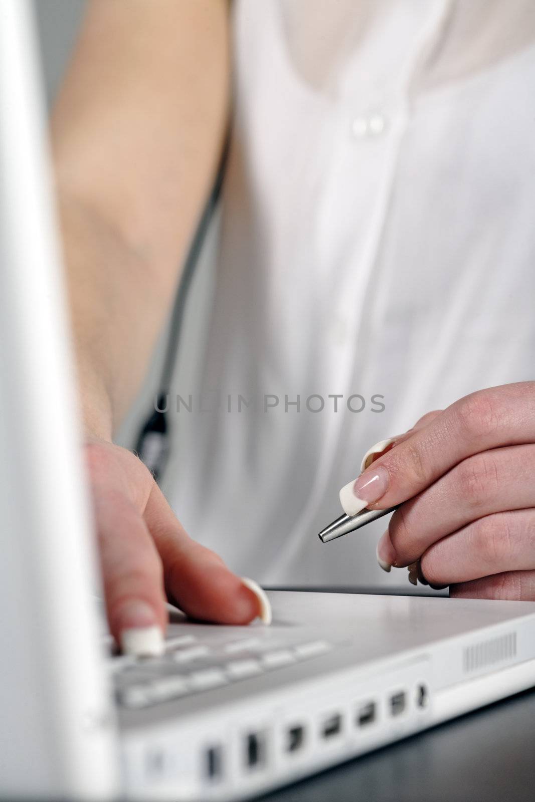 Woman using laptop while holding  pen at work