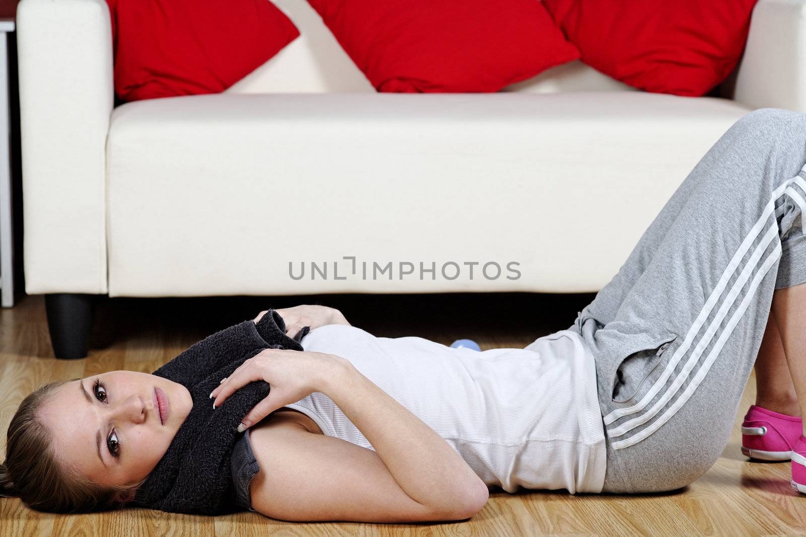 Young woman resting at home after exercise in fitness wear.