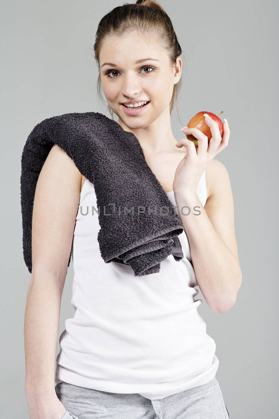 Young woman resting after exercise in fitness wear eating an apple