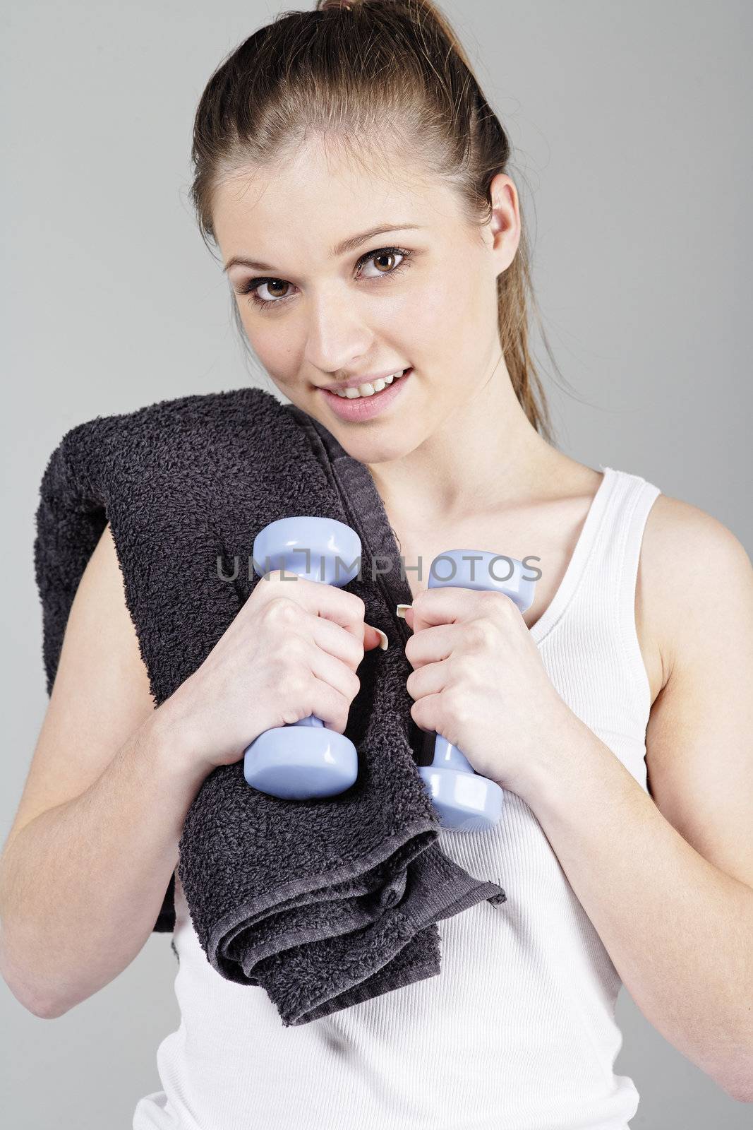 Young woman in fitness wear working out with coloured weights.