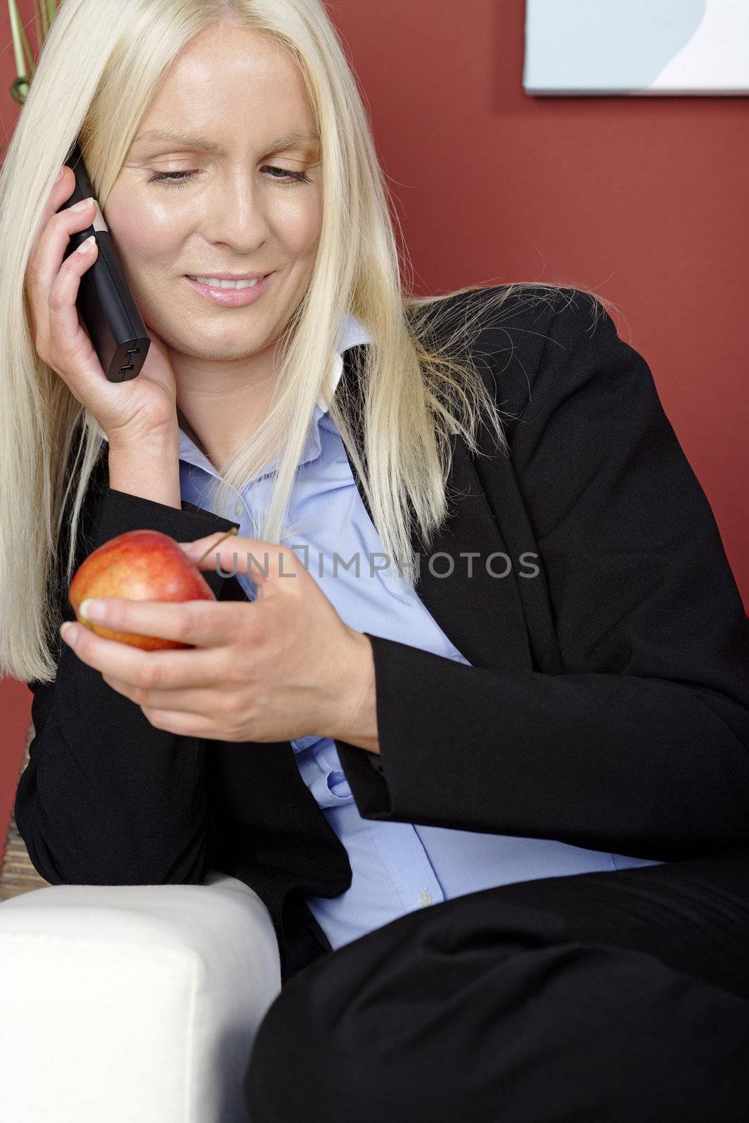 Young woman holding an apple and phone while relaxing at home