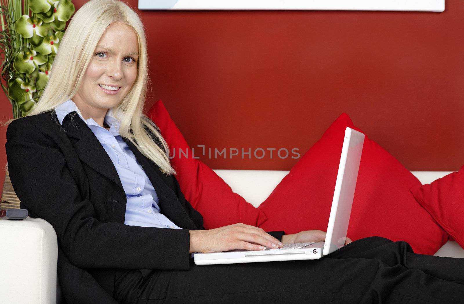 Woman sat on sofa using laptop by studiofi