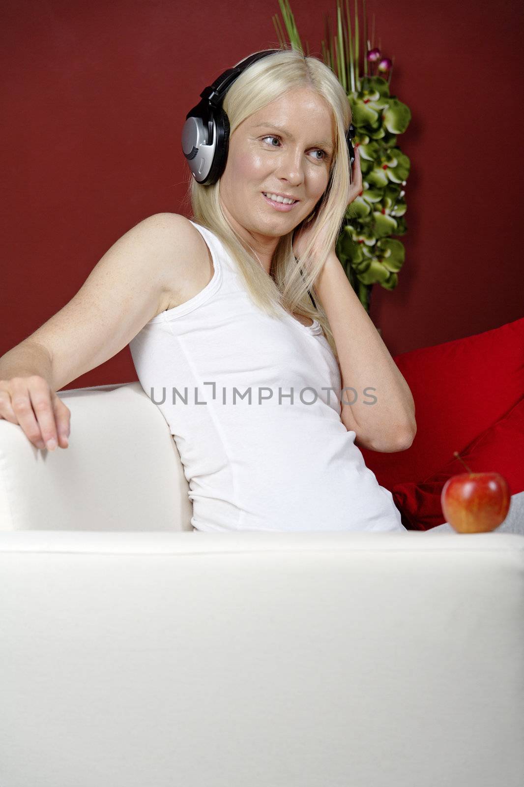 Young woman on sofa at home listening to music with headphones