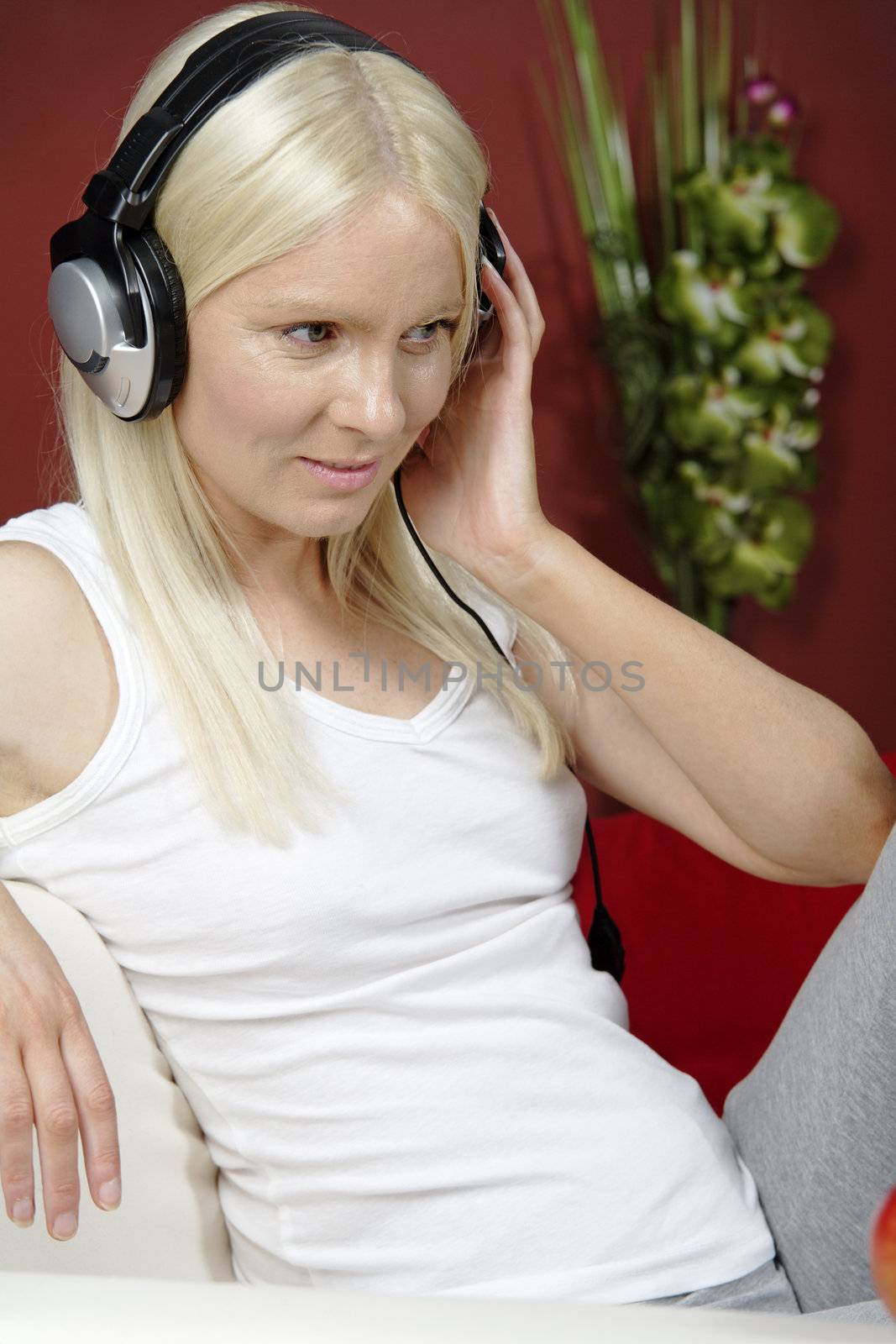 Young woman on sofa at home listening to music with headphones