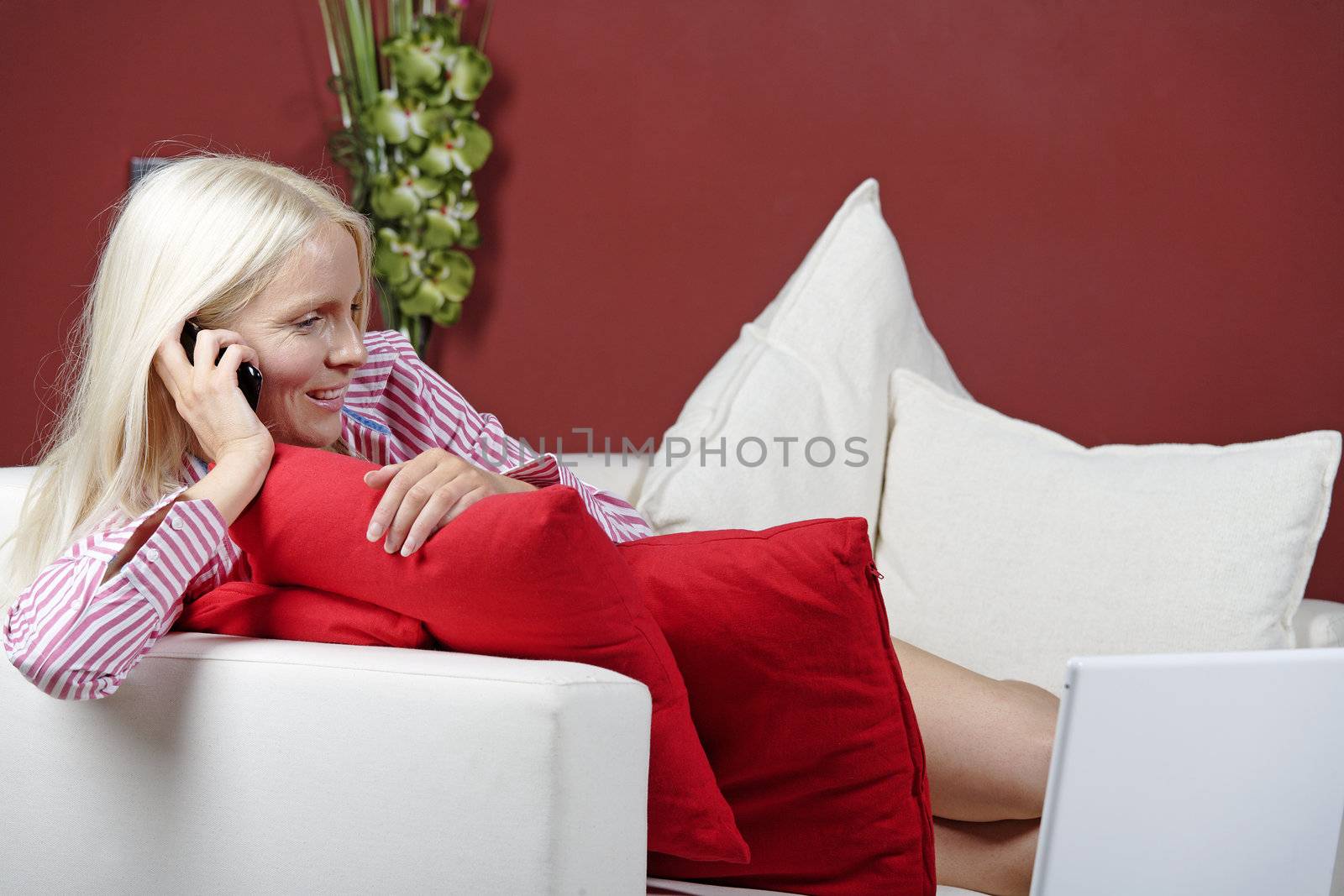 Young woman at home on sofa chatting on the mobile