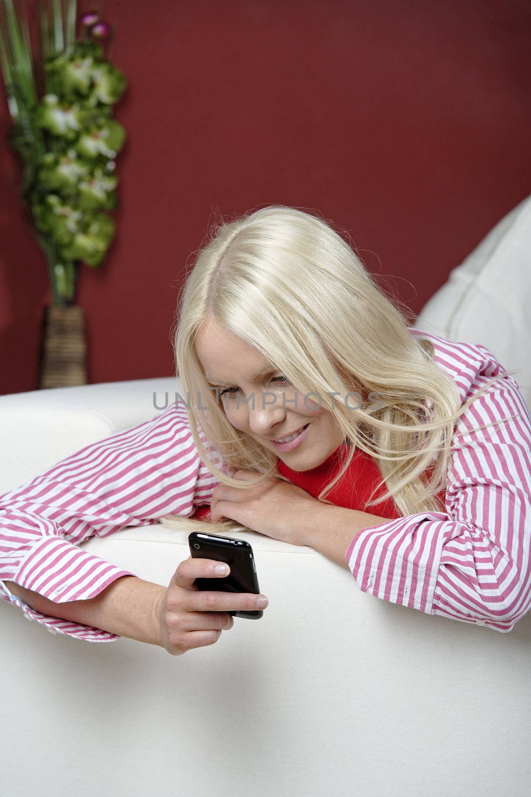 Young woman texting on her mobile phone, while resting on the sofa