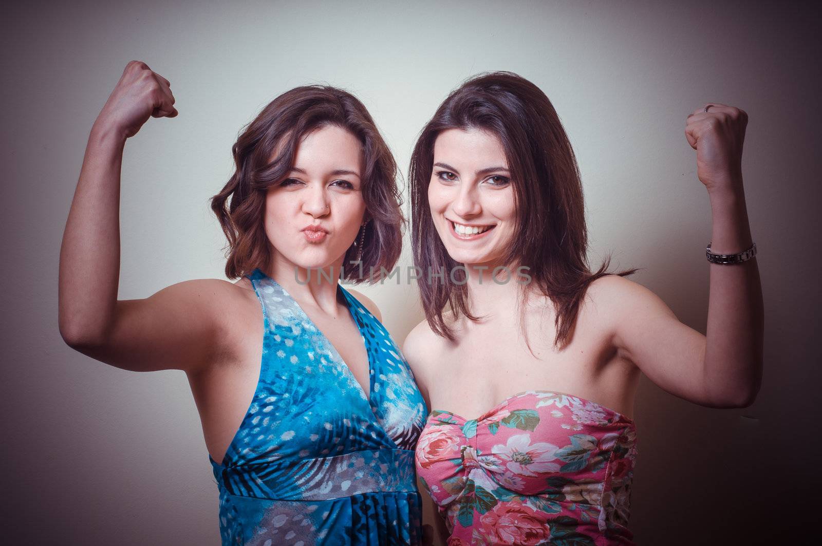 two beautiful girls showing muscle on gray background