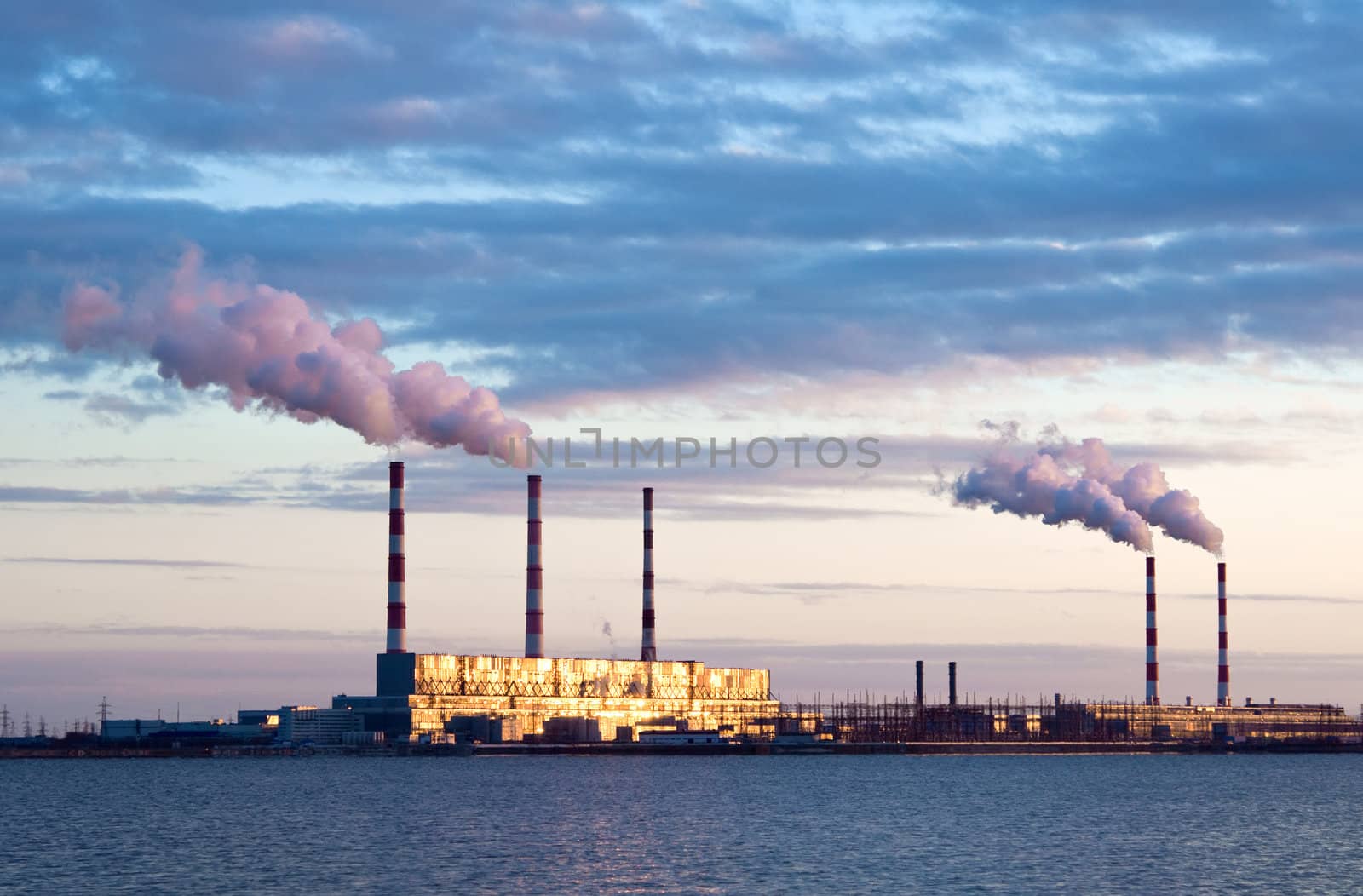 Thermal power station and smoke plume  lit golden sun rays.