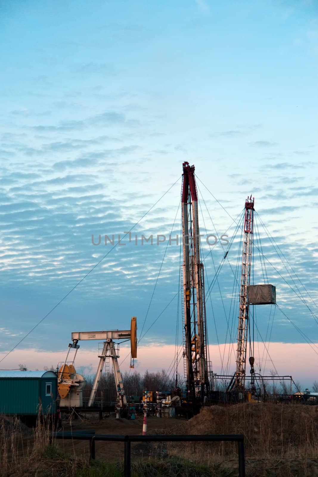 oil pump and drilling rigs at the sunset sky background. Russia, Western Siberia