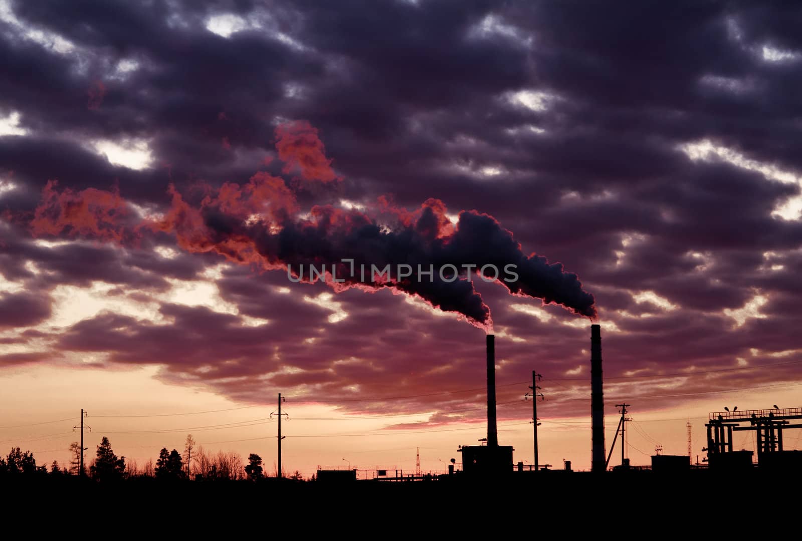 Pollution spewing into the air from industrial chimneys, at sunset.
