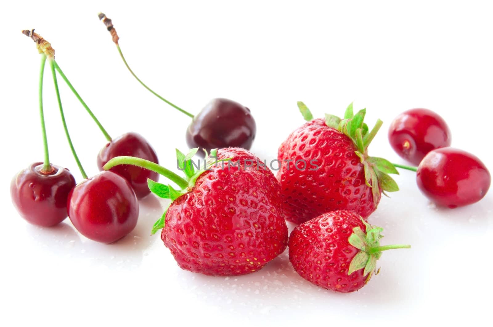 strawberries and cherries on a white background in droplets of water