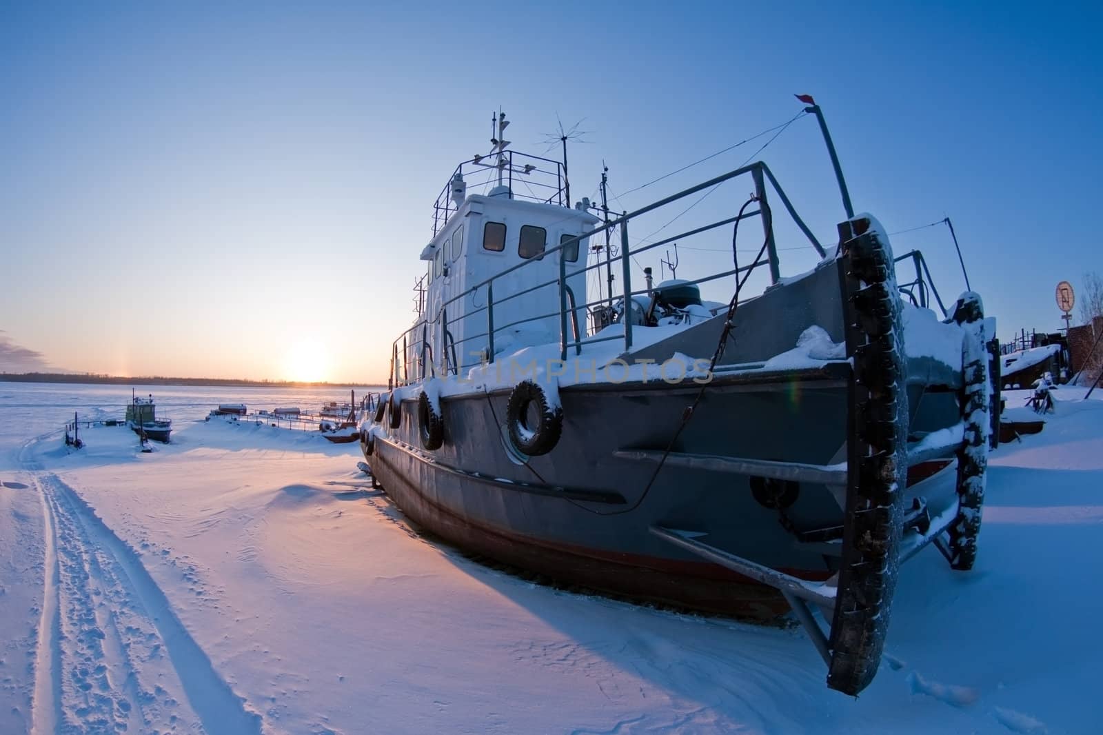 Ships covered with snow on coast Ob River, await  season of navigation. winter sunset, Siberia, Surgut city.