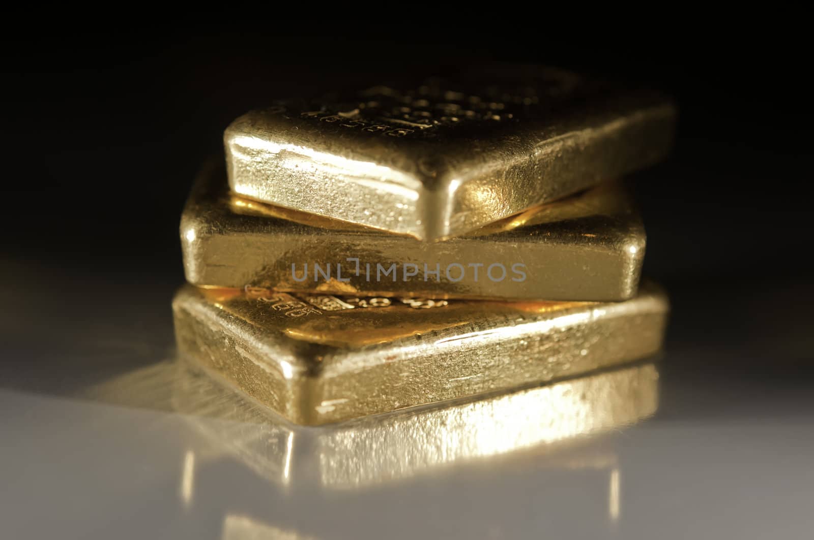 three gold ingots on a dark grey background. shallow depth of field.