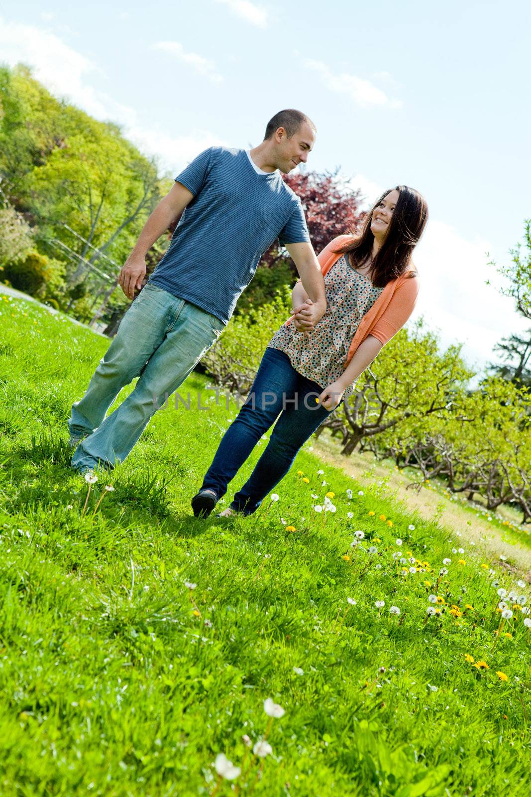Young happy couple enjoying each others company outdoors through a country field.
