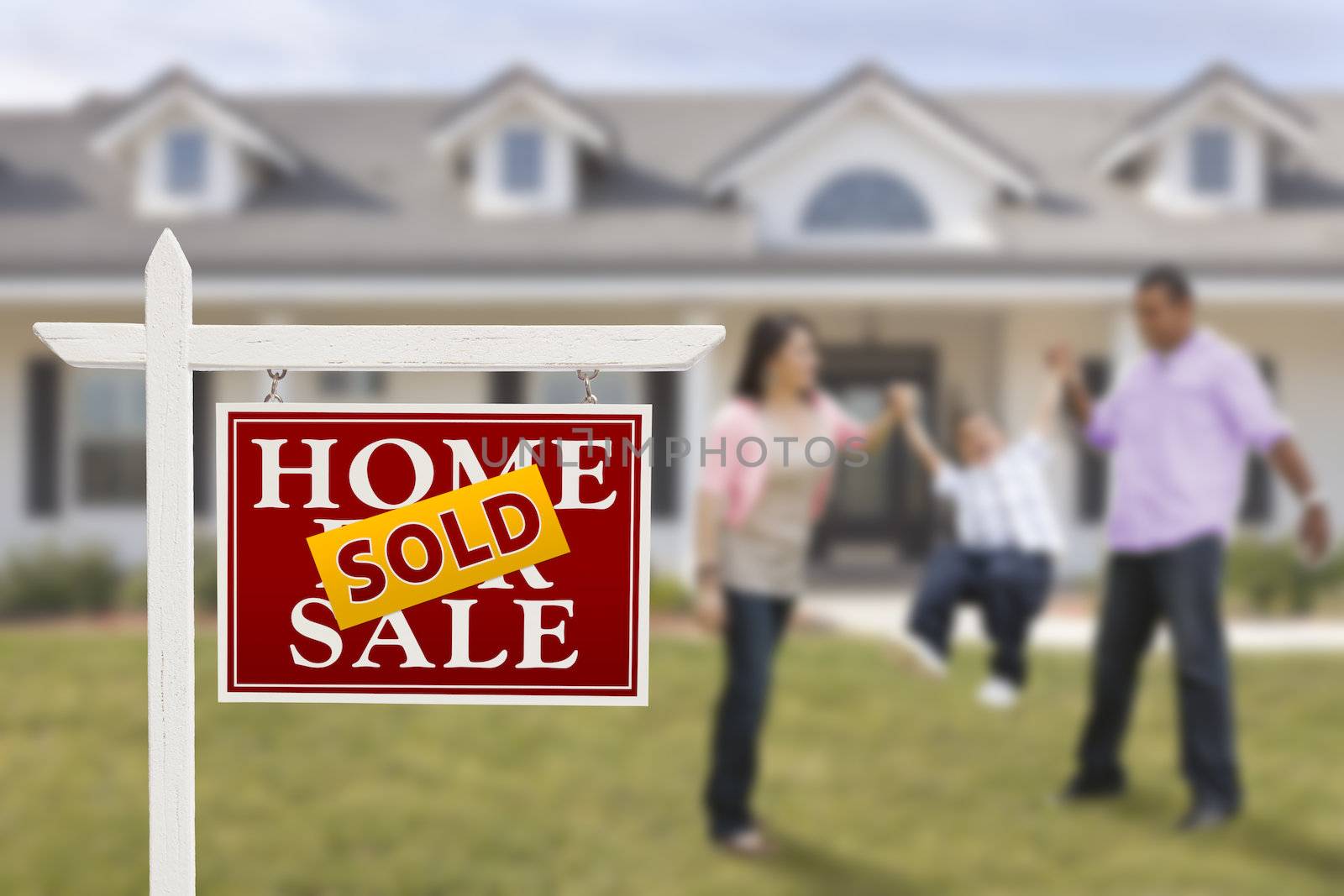 Sold Real Estate Sign and Playful Hispanic Family in Front of House.