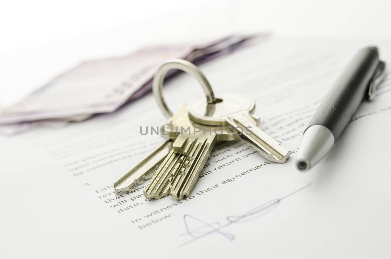 Keys of a new house on a signed contract of house sale with money in background. Concept of closed deal.