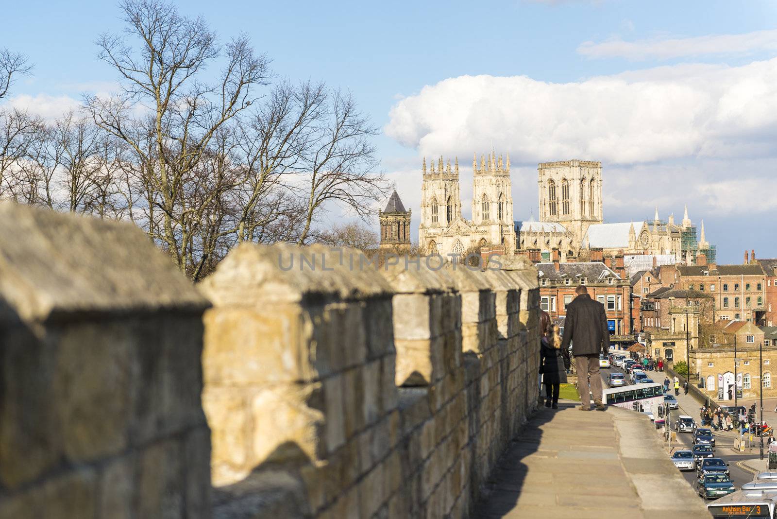 YORK, UK - MARCH 30: Pedestrians walking on the mediaeval wall that surrounds the city, with York Minster in the background. March 30, 2013 in York.