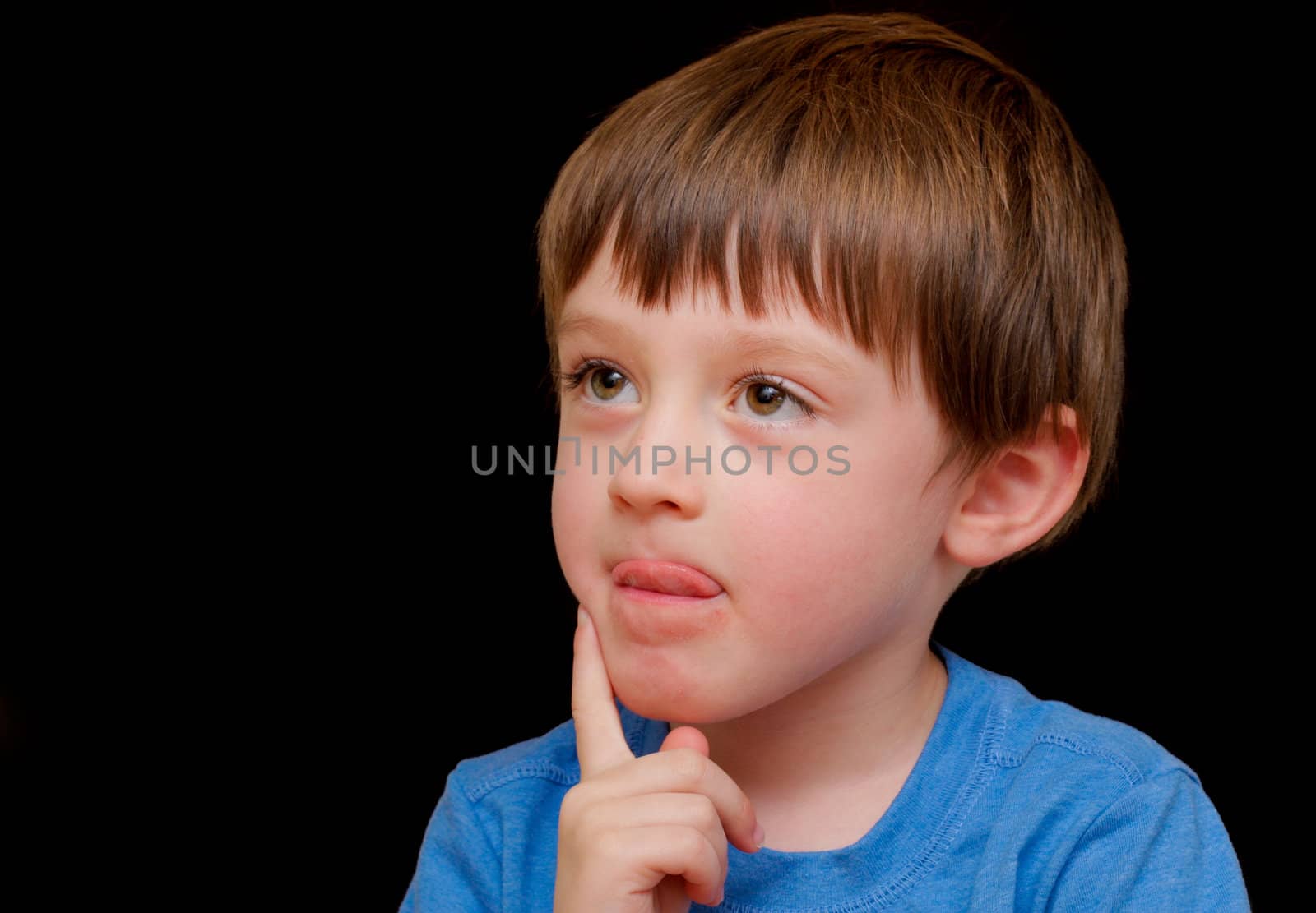 A curious four year old boy on a black background