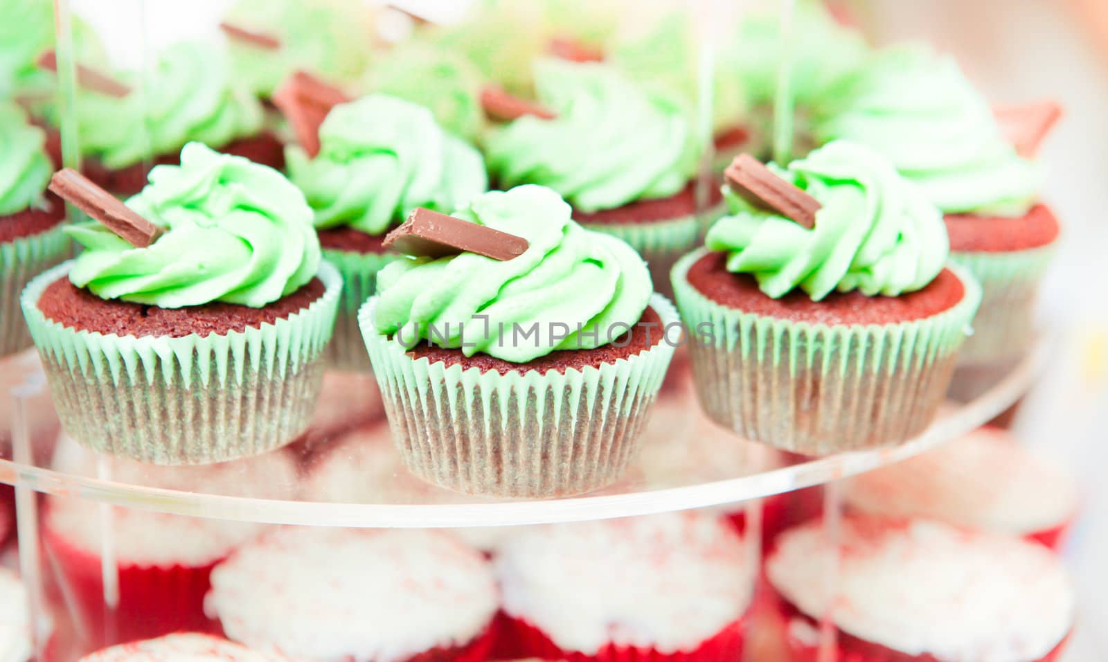 Selection of fresh iced cup cakes on a stand at a wedding