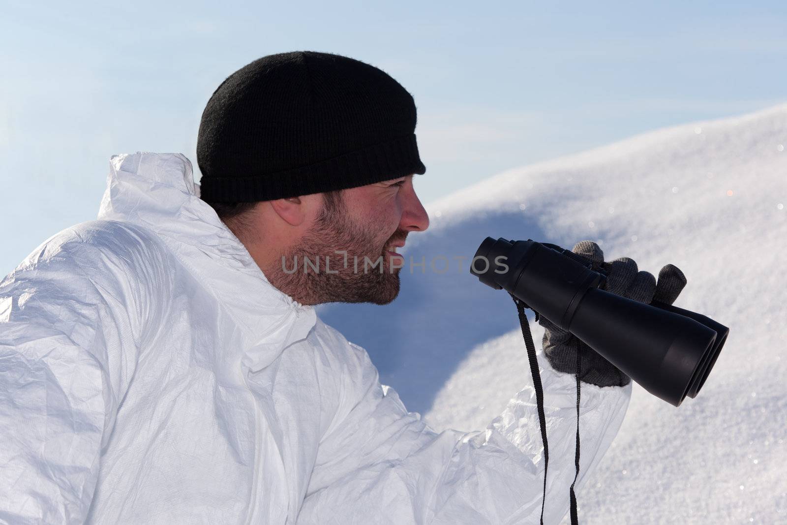 Commandos in white camouflage looking through binoculars in the mountains on the white snow. Portrait in Profile