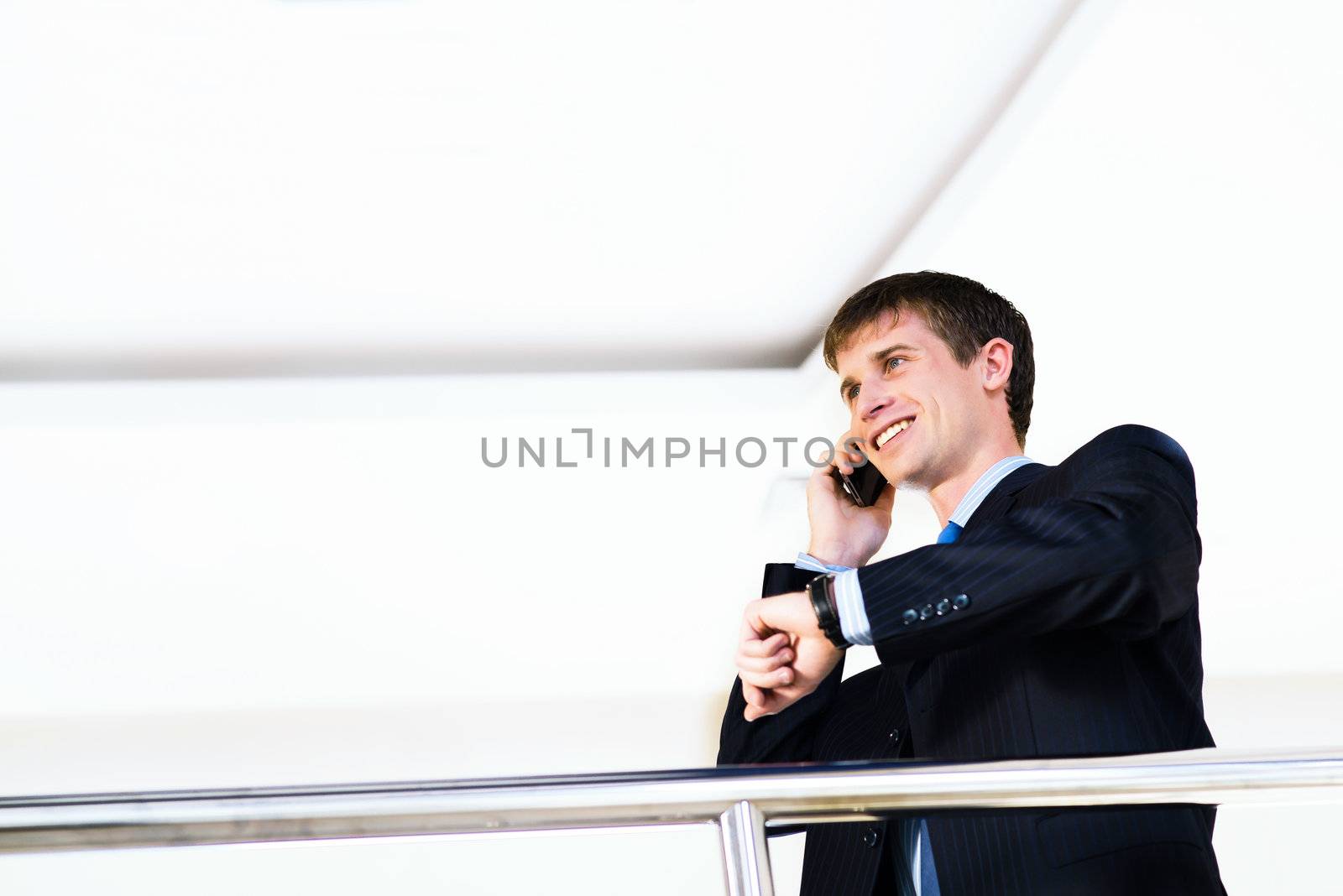 Businessman talking on cell phone and looking at his watch