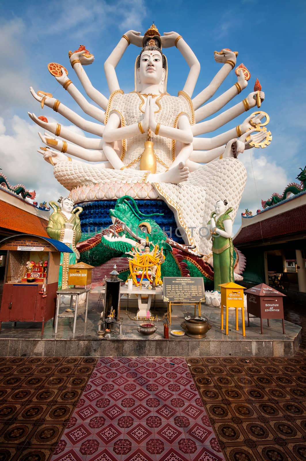 Eighteen arms Buddha over blue sky by johnnychaos