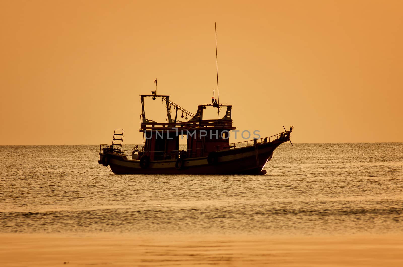 Sunset with boat on tropical beach by johnnychaos