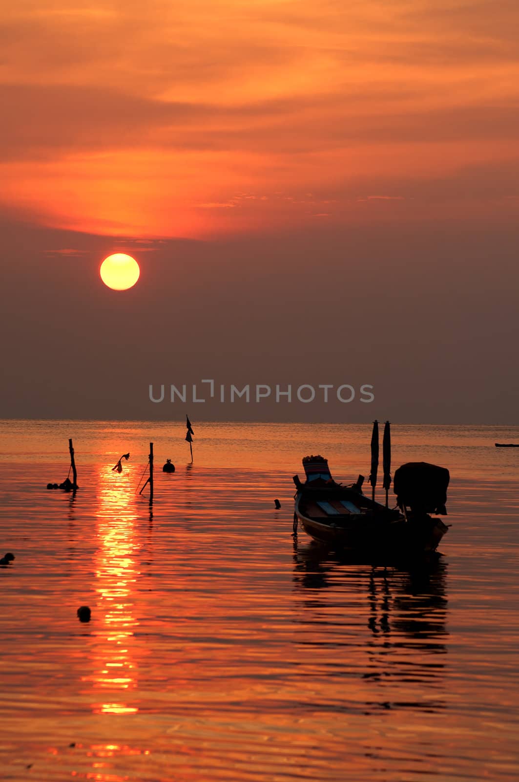 Sunset with boat on tropical beach by johnnychaos