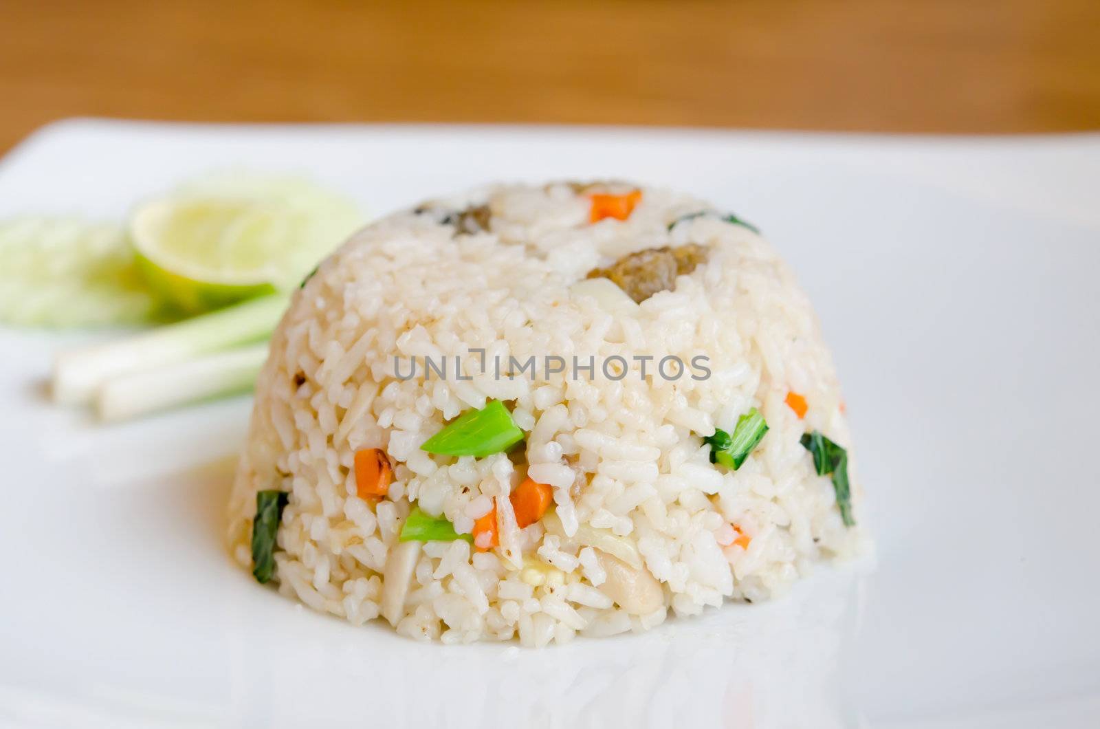 Mixed cooked rice with fried fish and sauce , served with fresh vegetable on dish