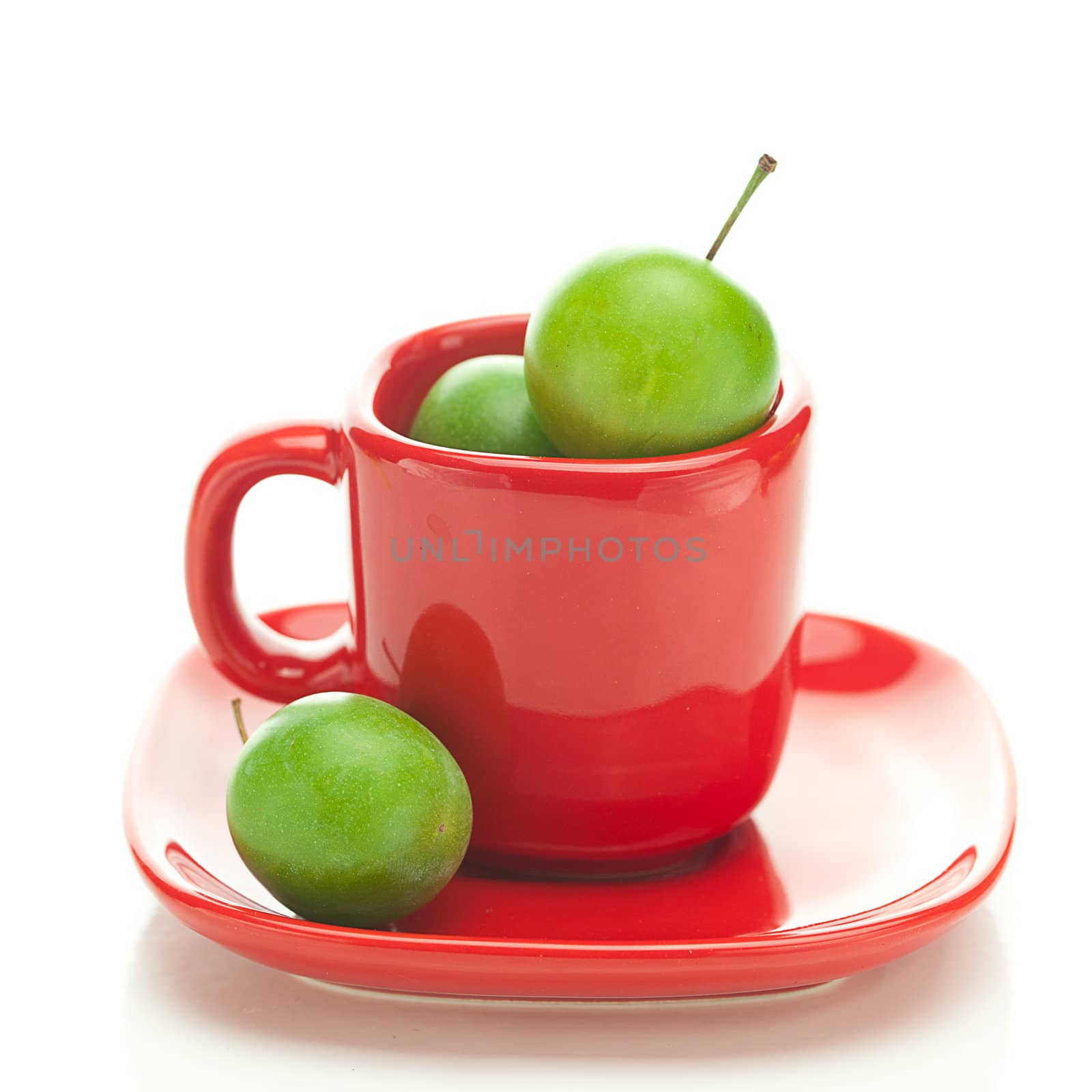 green plum  in the red cup isolated on white by jannyjus