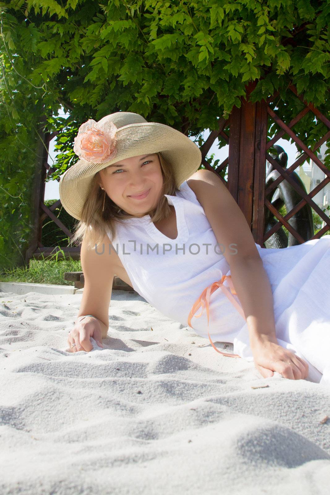 Woman with hat lying on white sand relaxing