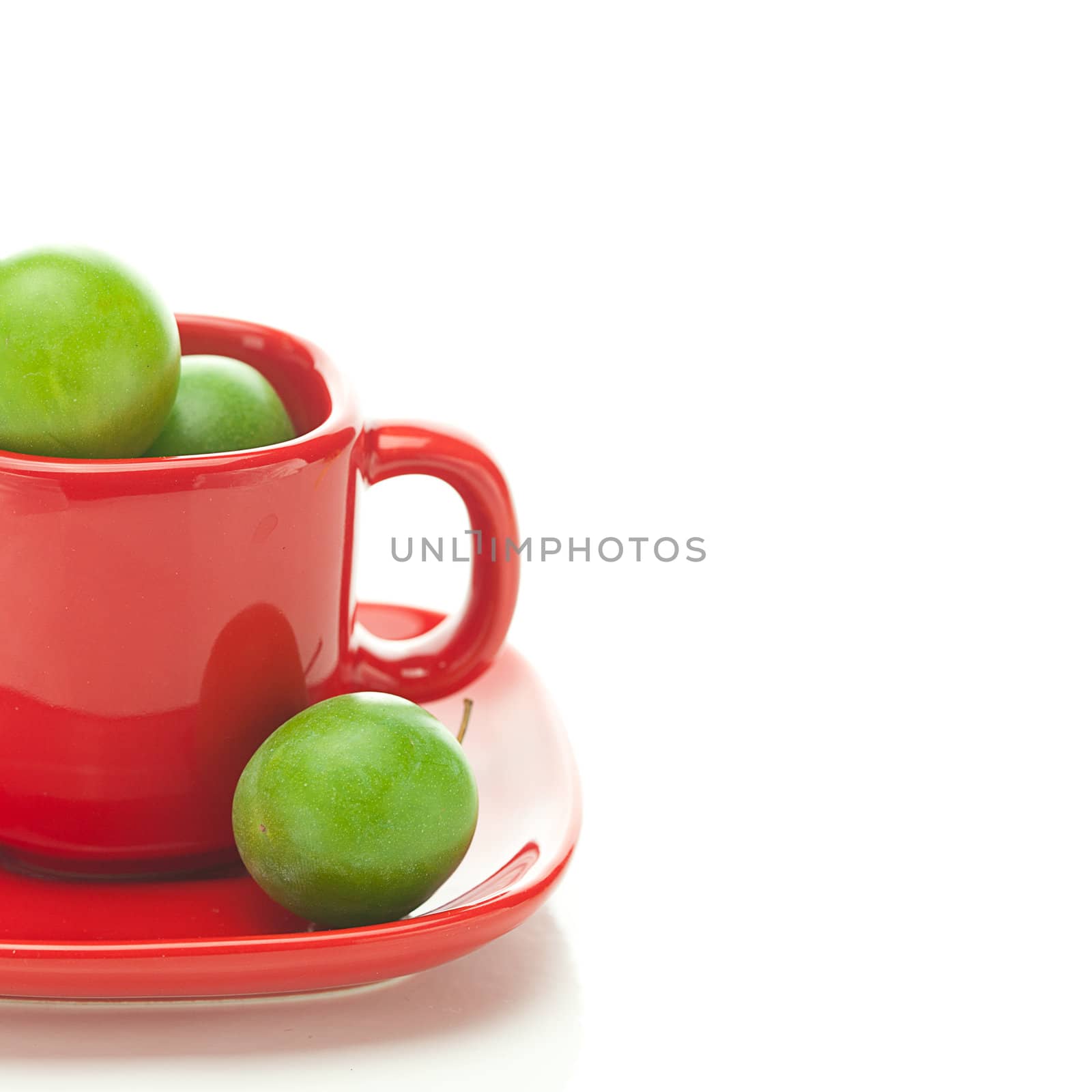 green plum  in the red cup isolated on white by jannyjus