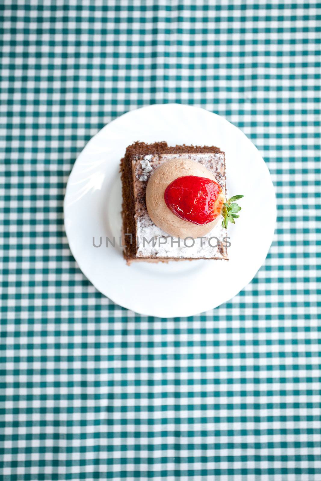 beautiful cake with strawberry on plaid fabric