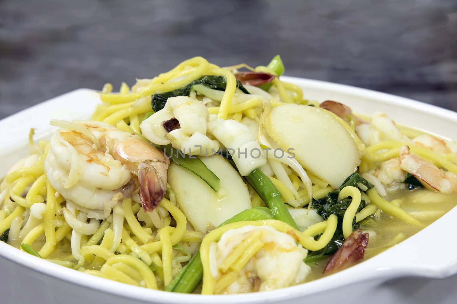 Hokkien Mee Stir Fry Yellow Noodles with Prawns Squids Fishcake and Green Vegetables Side View Closeup
