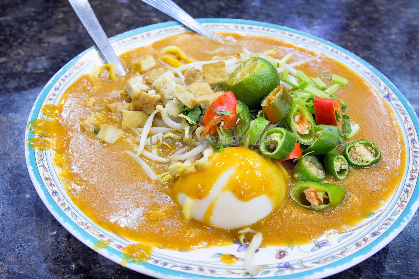 Malay Mee Rebus Noodle Dish Garnished with Cut Chili Peppers Tofu Chinese Celery and Hard Boiled Egg
