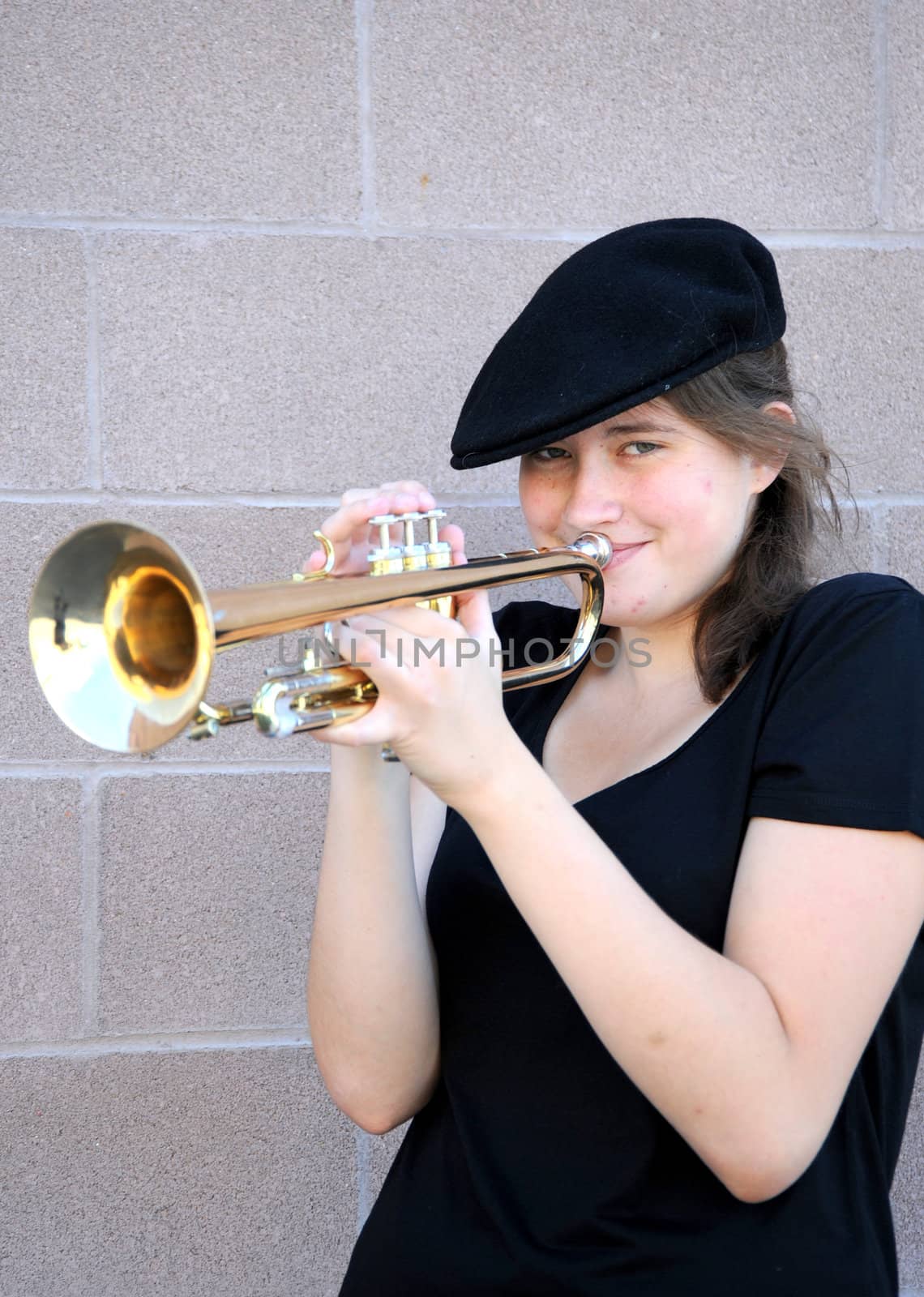 Female trumpet player blowing her horn outdoors.