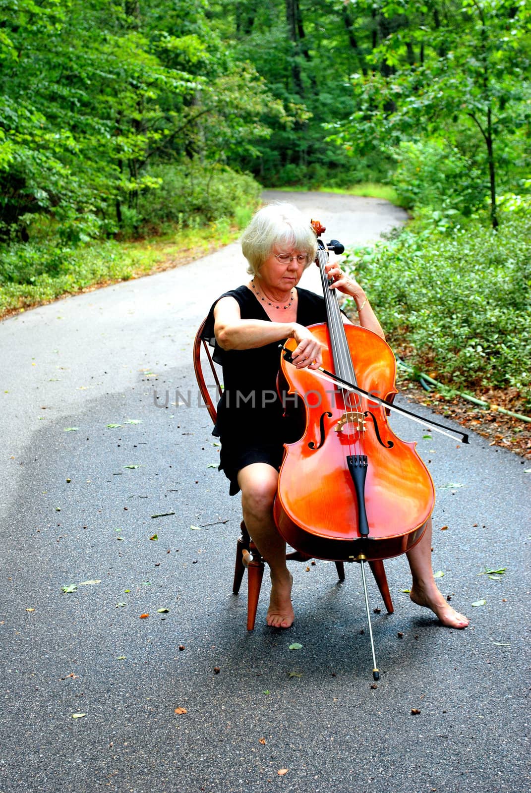 Female cellist posing with her cello outside.